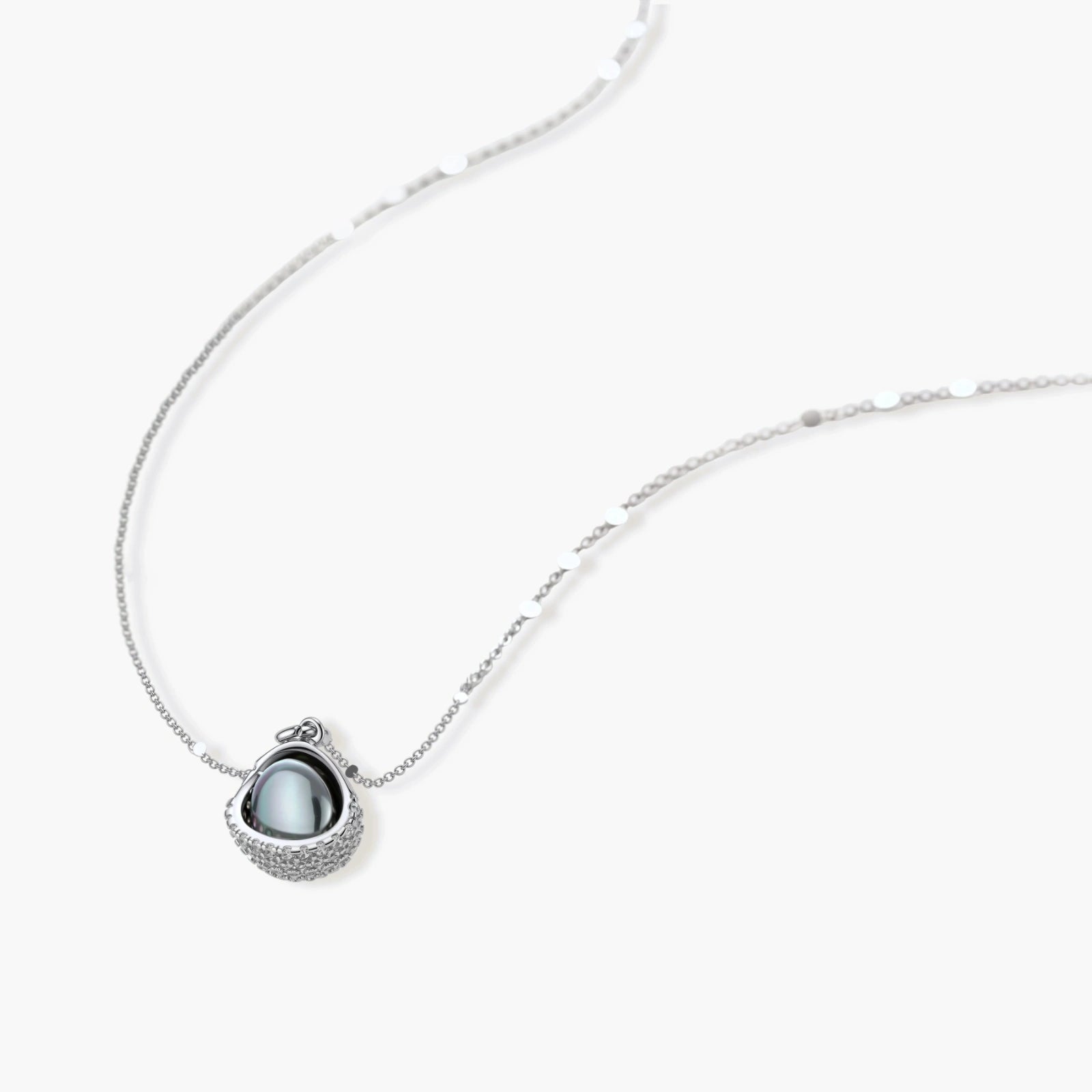 White gold plated spherical jewelry set with zirconia crystal pavé and dark lustrous centers on neutral background.