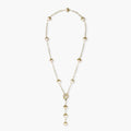 Gold-plated lariat necklace with baroque pearls and textured caps on cream background, showing adjustable Y-shaped design.