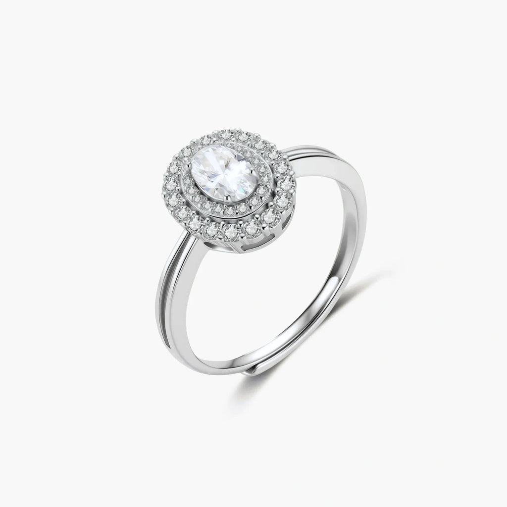 Sterling silver ring with oval moissanite center stone surrounded by double halo of sparkling stones on neutral background.