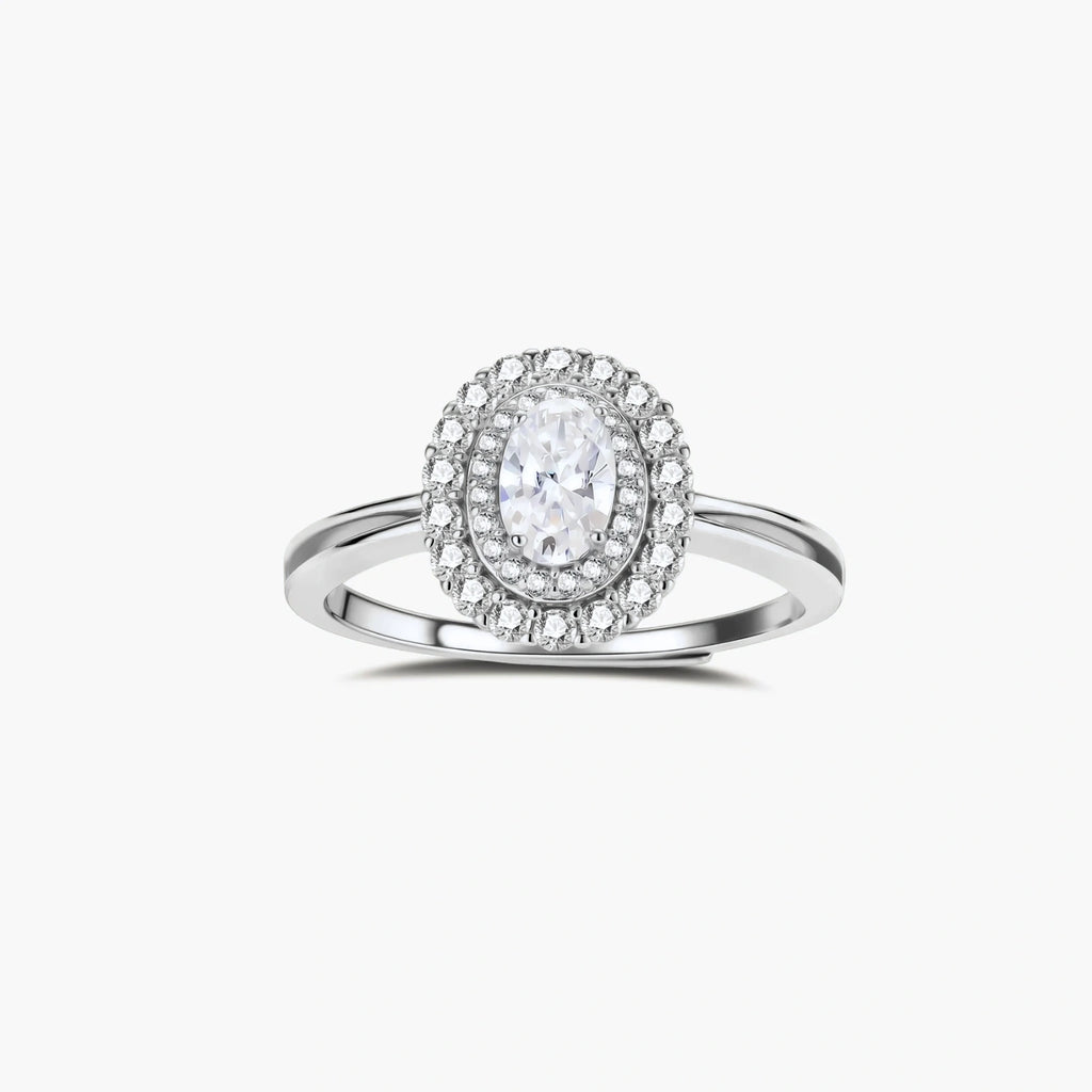Sterling silver ring with oval moissanite center stone surrounded by double halo of sparkling stones on neutral background.