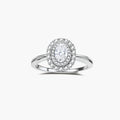 Sterling silver ring with oval moissanite center stone surrounded by double halo of sparkling stones on neutral background.