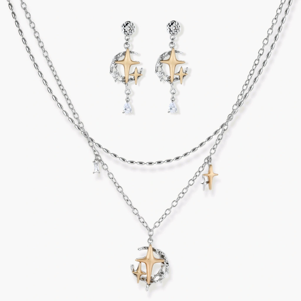 Delicate eco-brass jewelry set featuring gold star and silver moon crescents with clear zirconia crystal drops on cream background