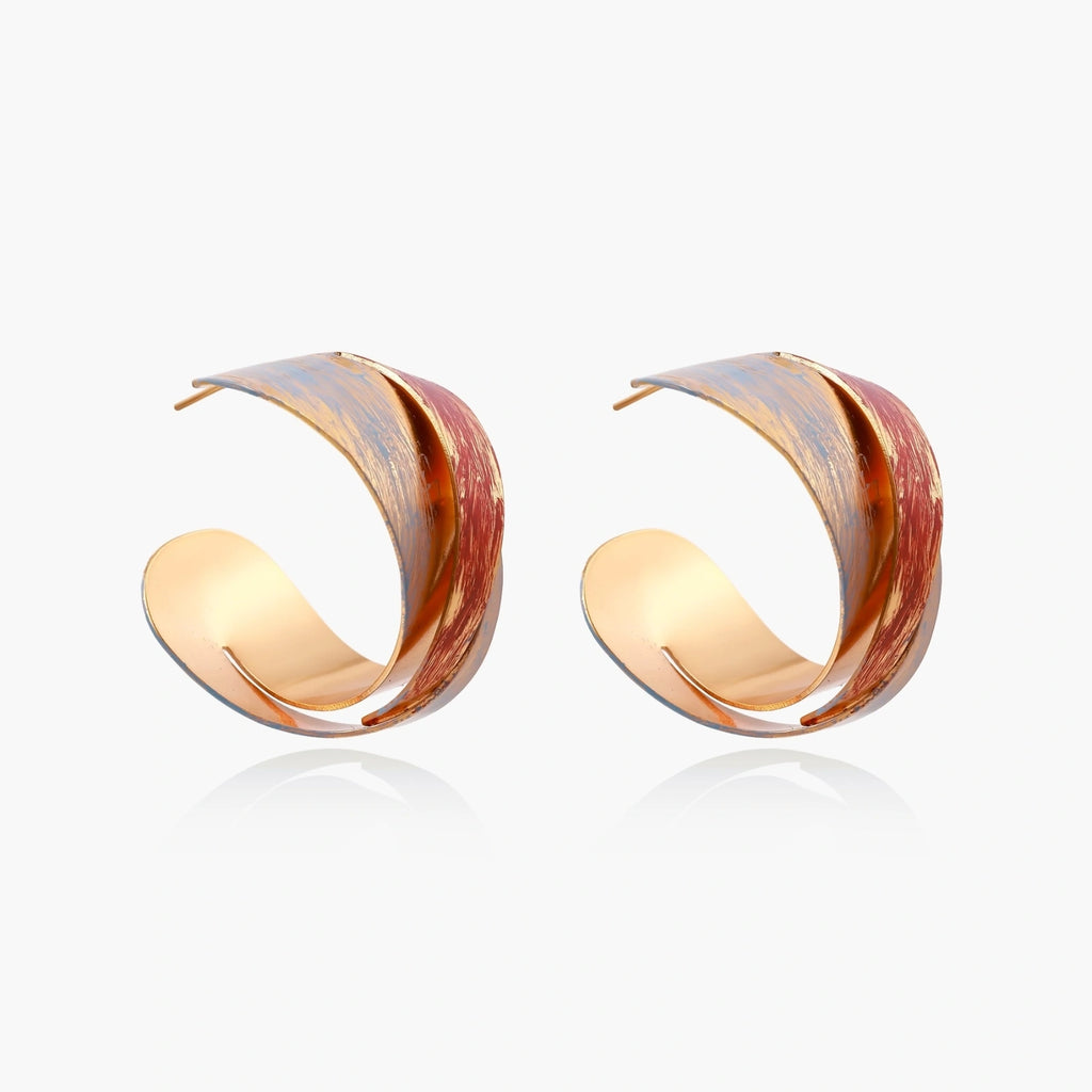 Sculptural gold-plated hoop earrings with diagonal purple and coral enamel stripes in twisted ribbon design