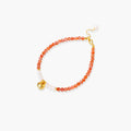 Beaded bracelet with coral-orange carnelian stones, white pearls, and gold heart charm on cream background
