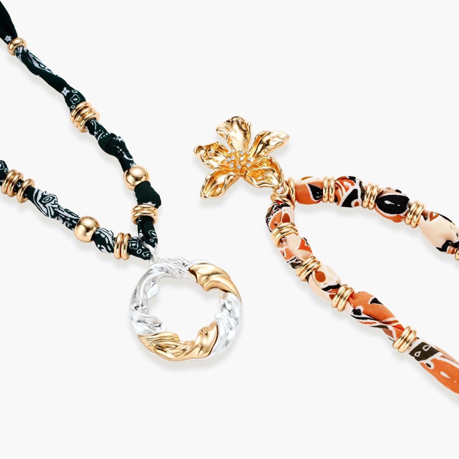 Vibrant patterned fabric necklace with gold-toned flower pendant featuring rhinestone center on white background