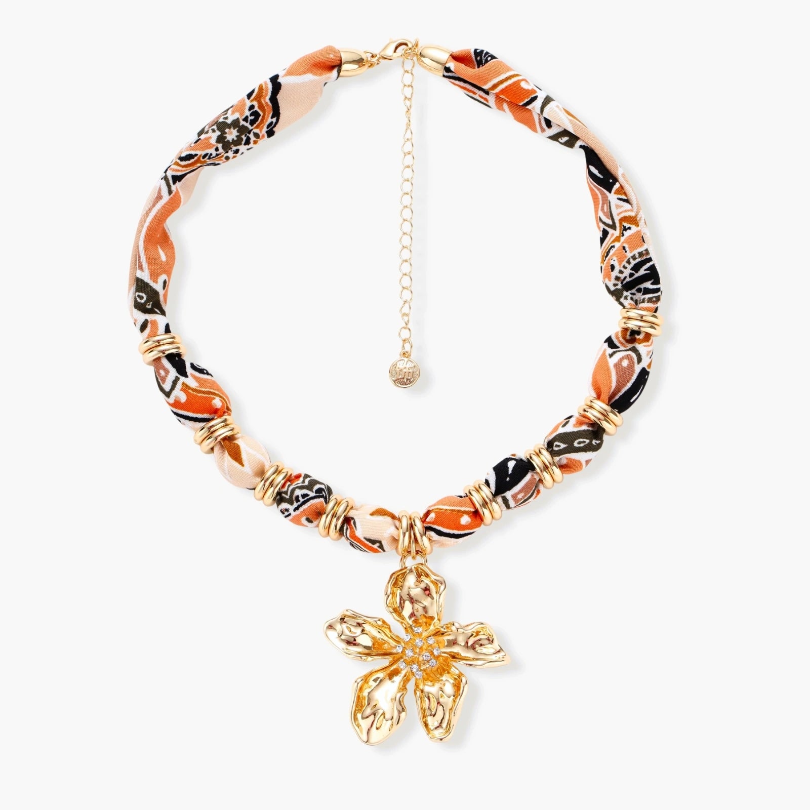 Vibrant patterned fabric necklace with gold-toned flower pendant featuring rhinestone center on white background