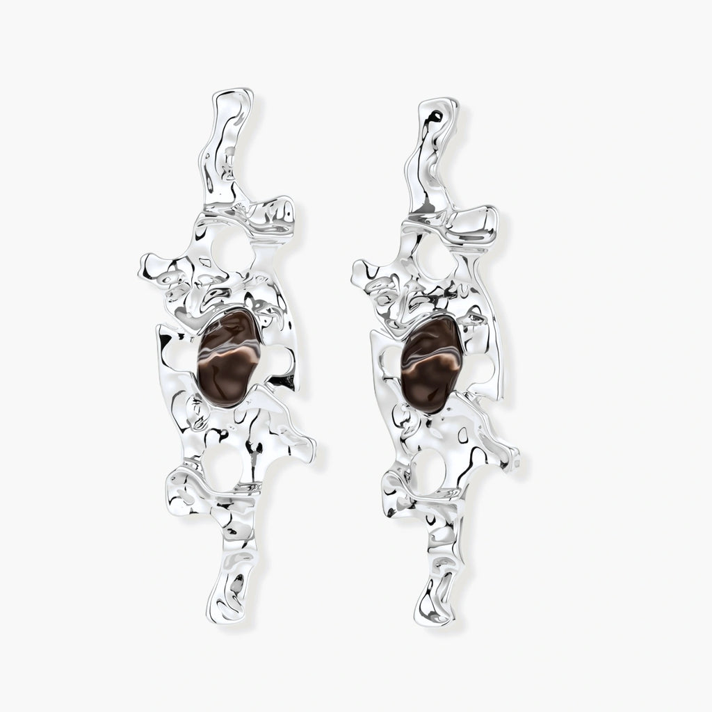 Flowing silver-toned earrings with organic liquid shapes and embedded brown resin stones on white background.