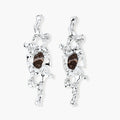 Flowing silver-toned earrings with organic liquid shapes and embedded brown resin stones on white background.
