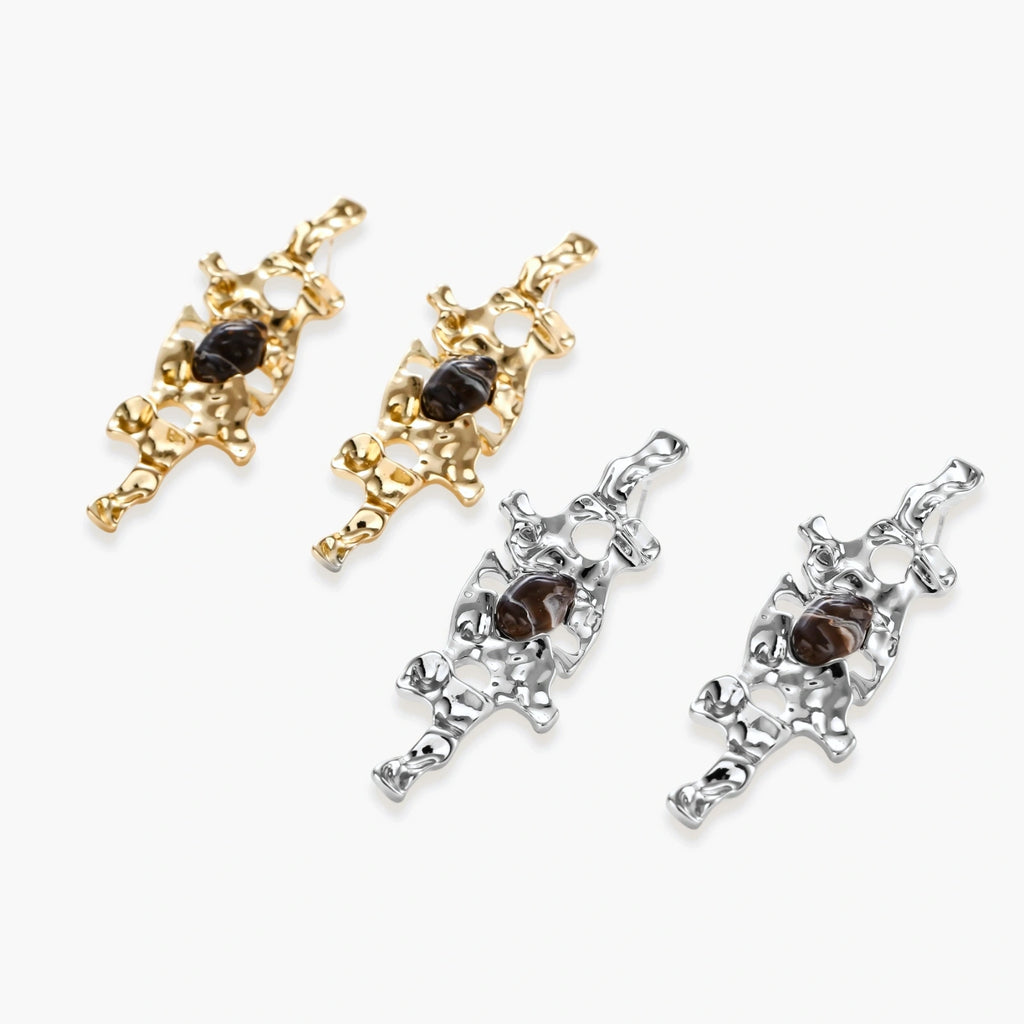 Flowing silver-toned earrings with organic liquid shapes and embedded brown resin stones on white background.