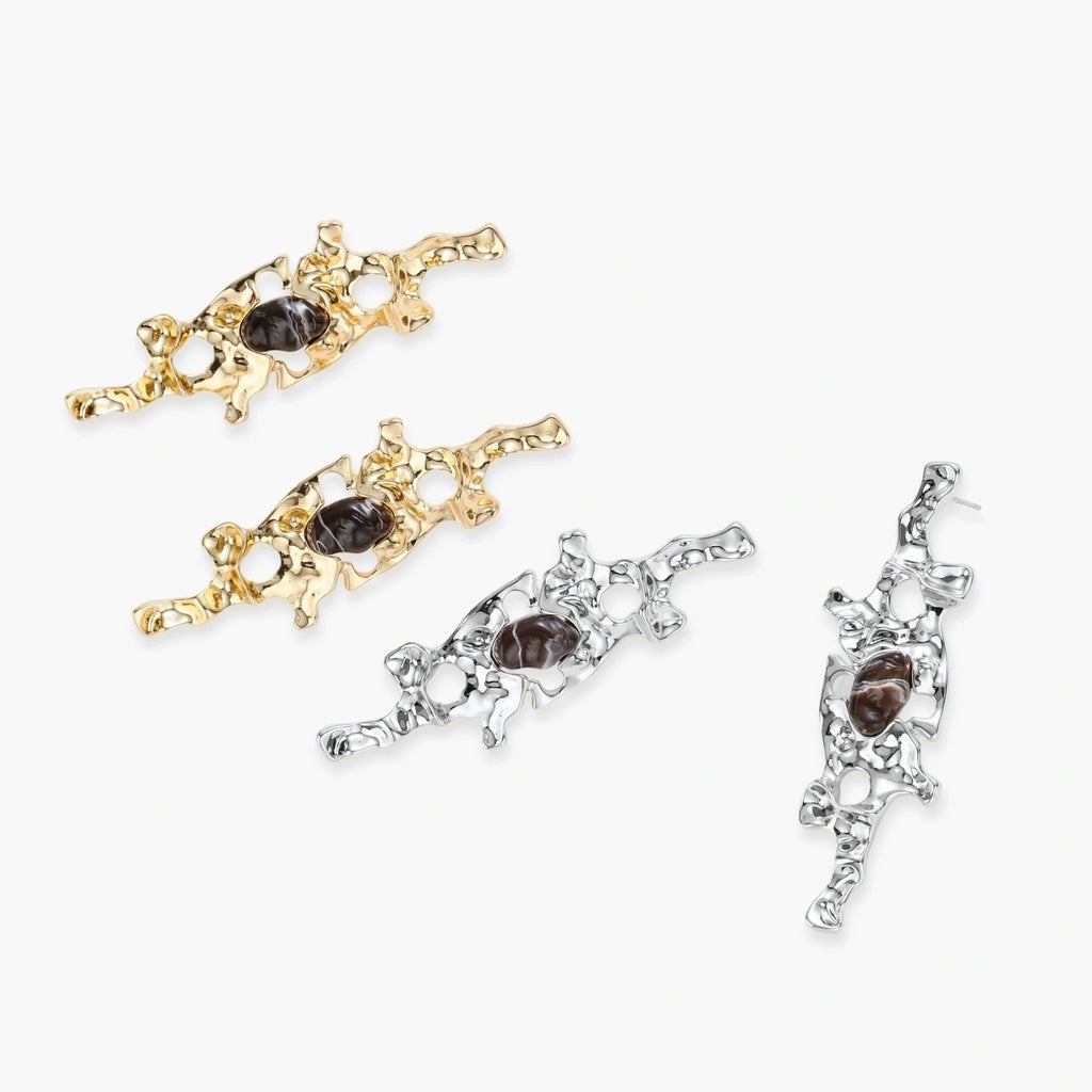 Flowing silver-toned earrings with organic liquid shapes and embedded brown resin stones on white background.