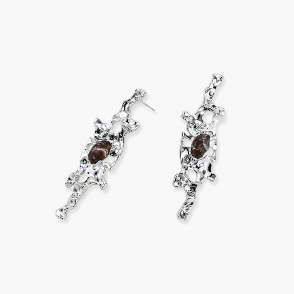 Flowing silver-toned earrings with organic liquid shapes and embedded brown resin stones on white background.