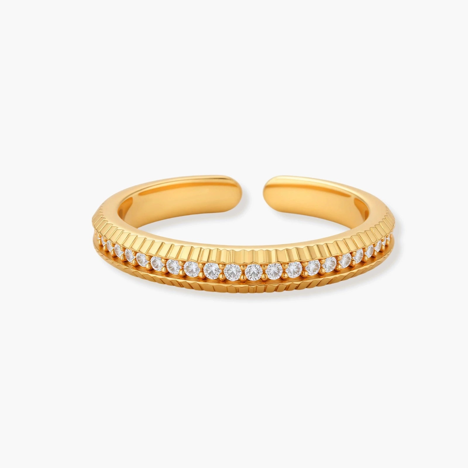 Adjustable gold-plated ring with row of sparkling crystals on ribbed band, shot against cream background