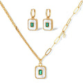 Gold-plated jewelry set with white enamel square pendants and emerald CZ stones on cream background.