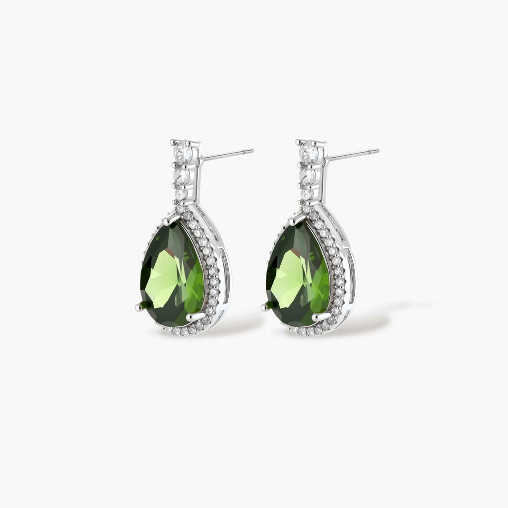 White gold plated jewelry set with green teardrop gemstones and cubic zirconia halos on cream background.