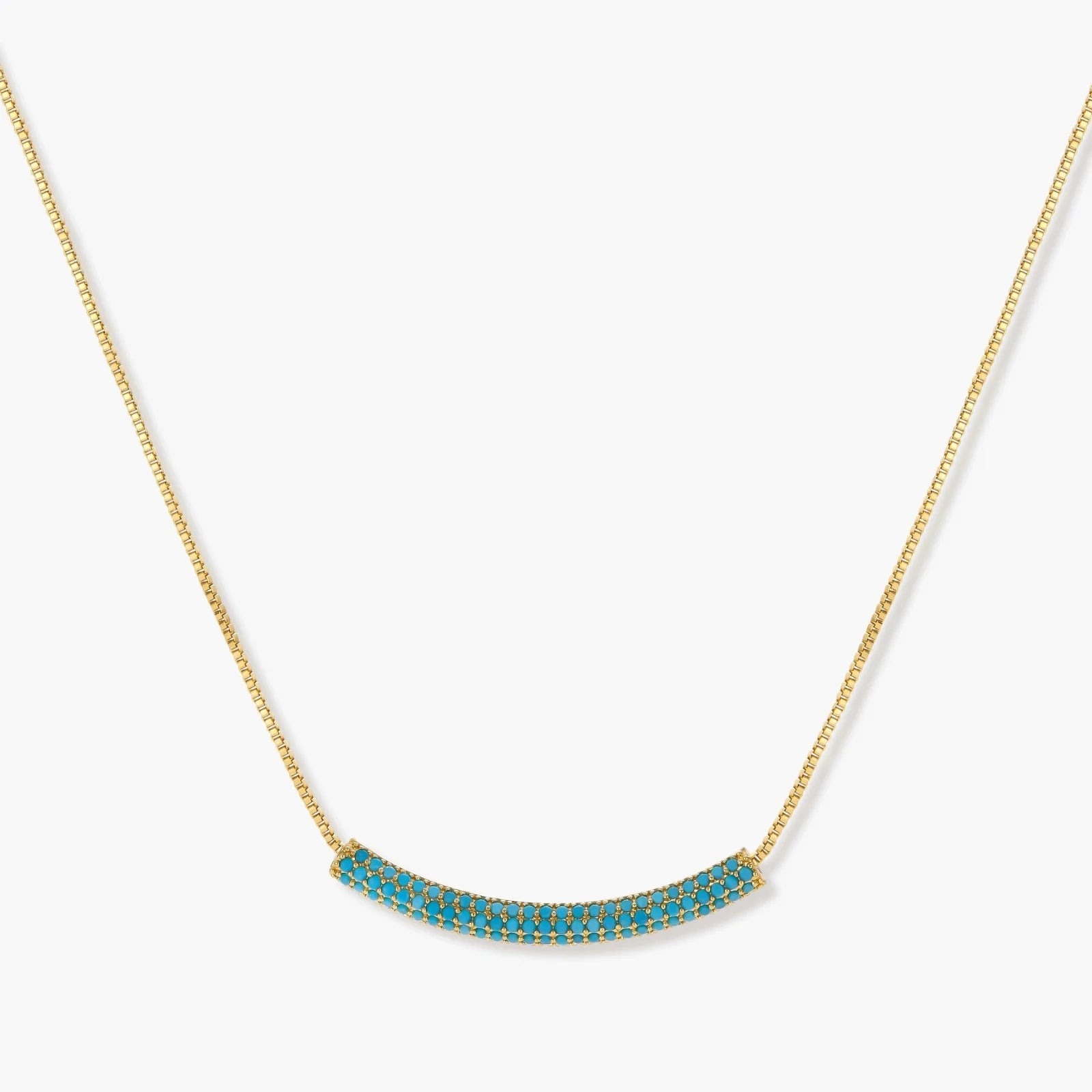 Gold-plated curved necklace and hoop earrings with turquoise cubic zirconia stones on white background.