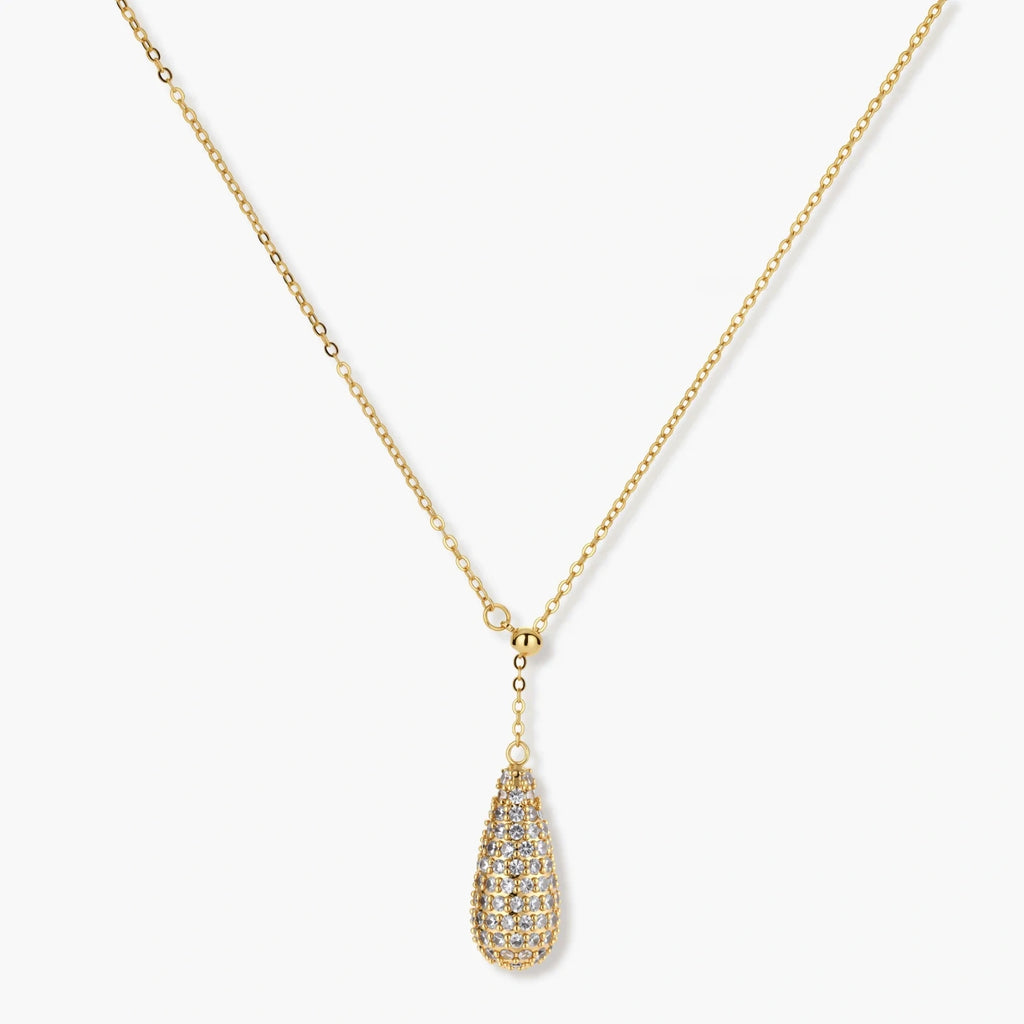 Gold-plated teardrop necklace and earrings covered in AAA cubic zirconia crystals on cream background.