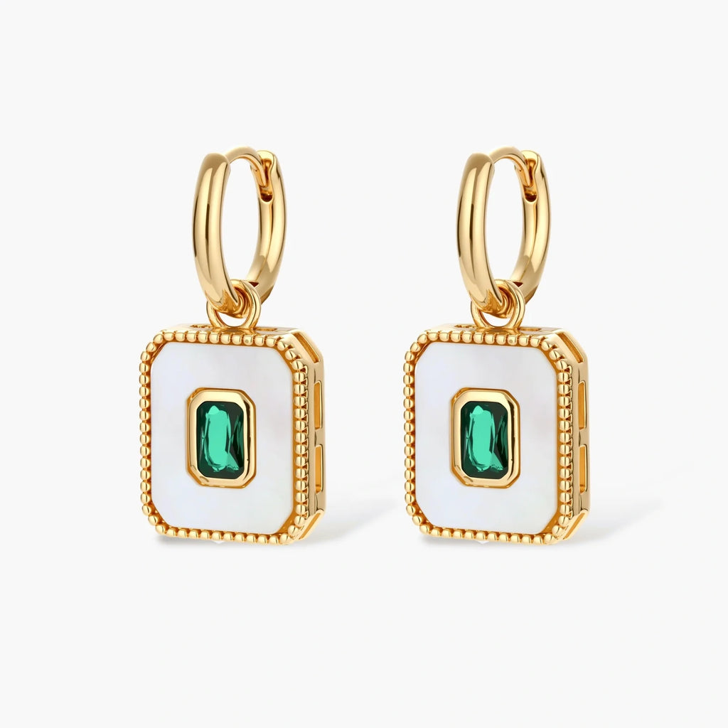 Gold-plated jewelry set with white enamel square pendants and emerald CZ stones on cream background.