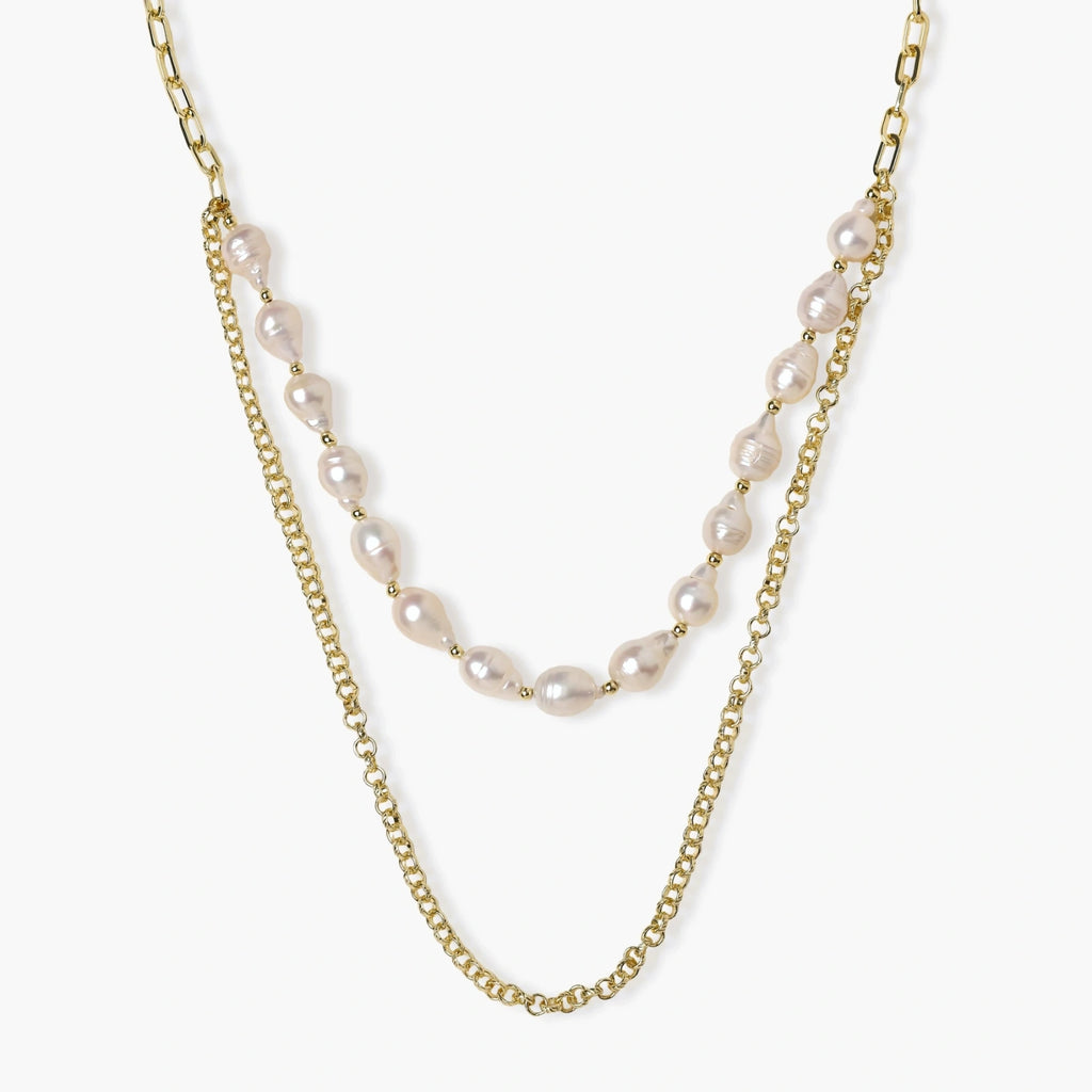 Layered gold chain necklace with organic baroque freshwater pearls and adjustable length on cream background