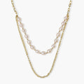 Layered gold chain necklace with organic baroque freshwater pearls and adjustable length on cream background