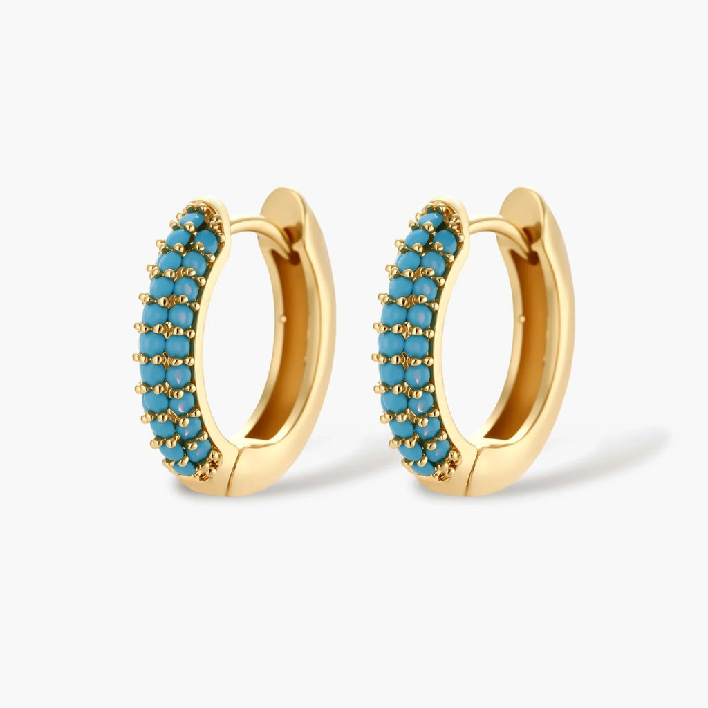 Gold-plated curved necklace and hoop earrings with turquoise cubic zirconia stones on white background.