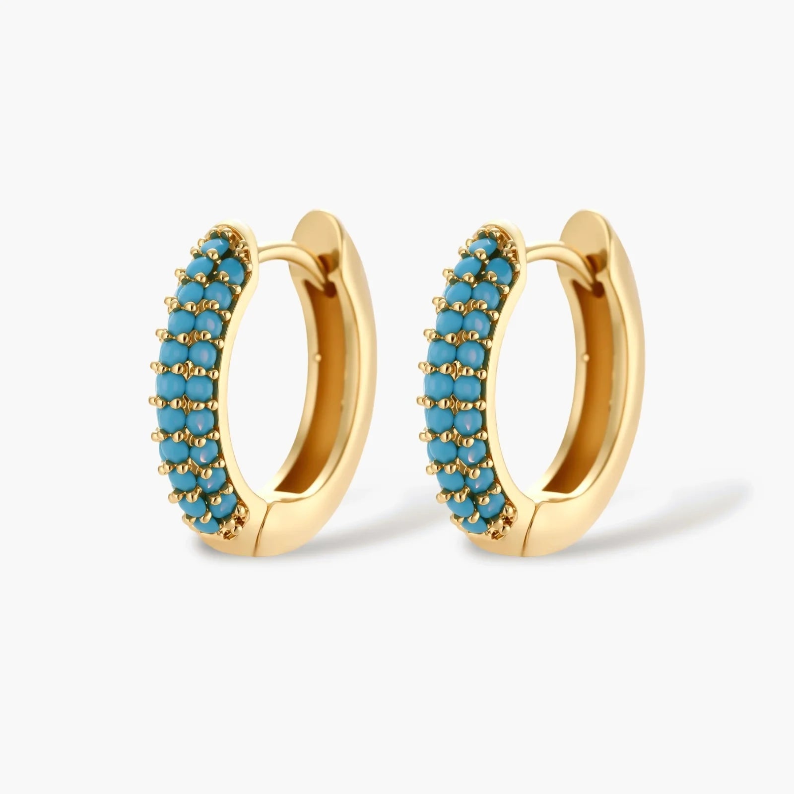 Gold-plated curved necklace and hoop earrings with turquoise cubic zirconia stones on white background.