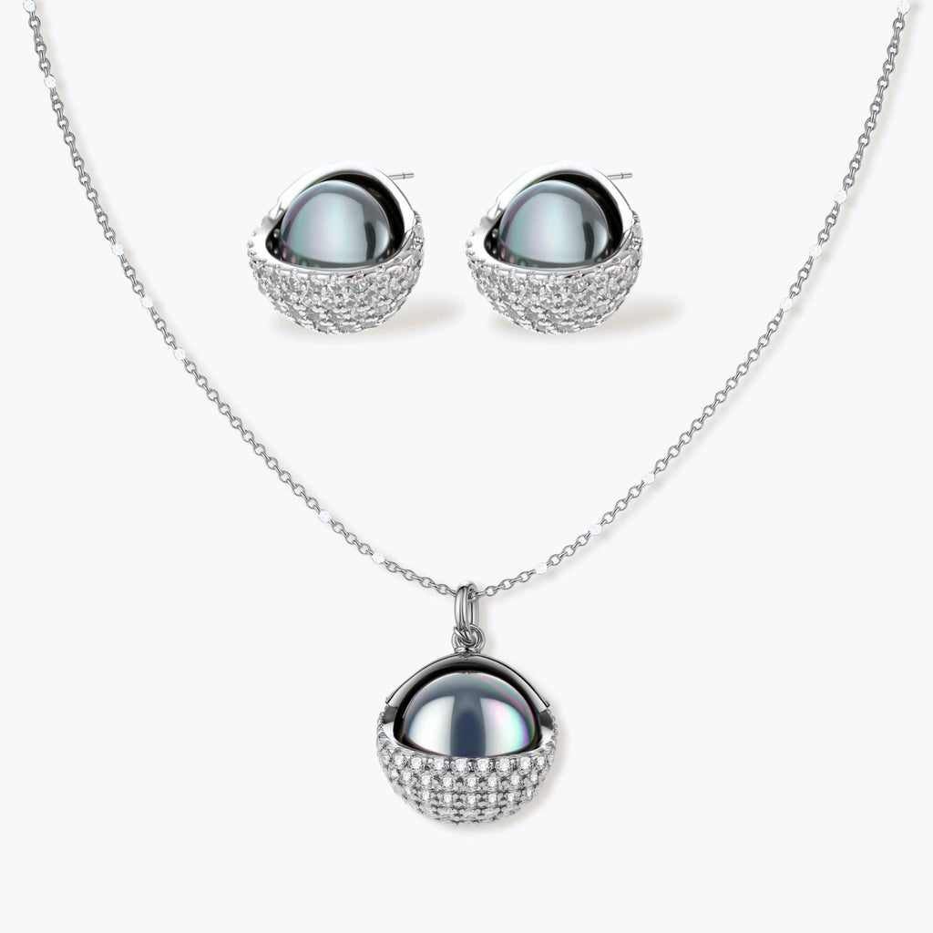 White gold plated spherical jewelry set with zirconia crystal pavé and dark lustrous centers on neutral background.