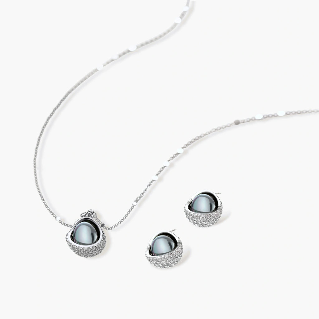 White gold plated spherical jewelry set with zirconia crystal pavé and dark lustrous centers on neutral background.